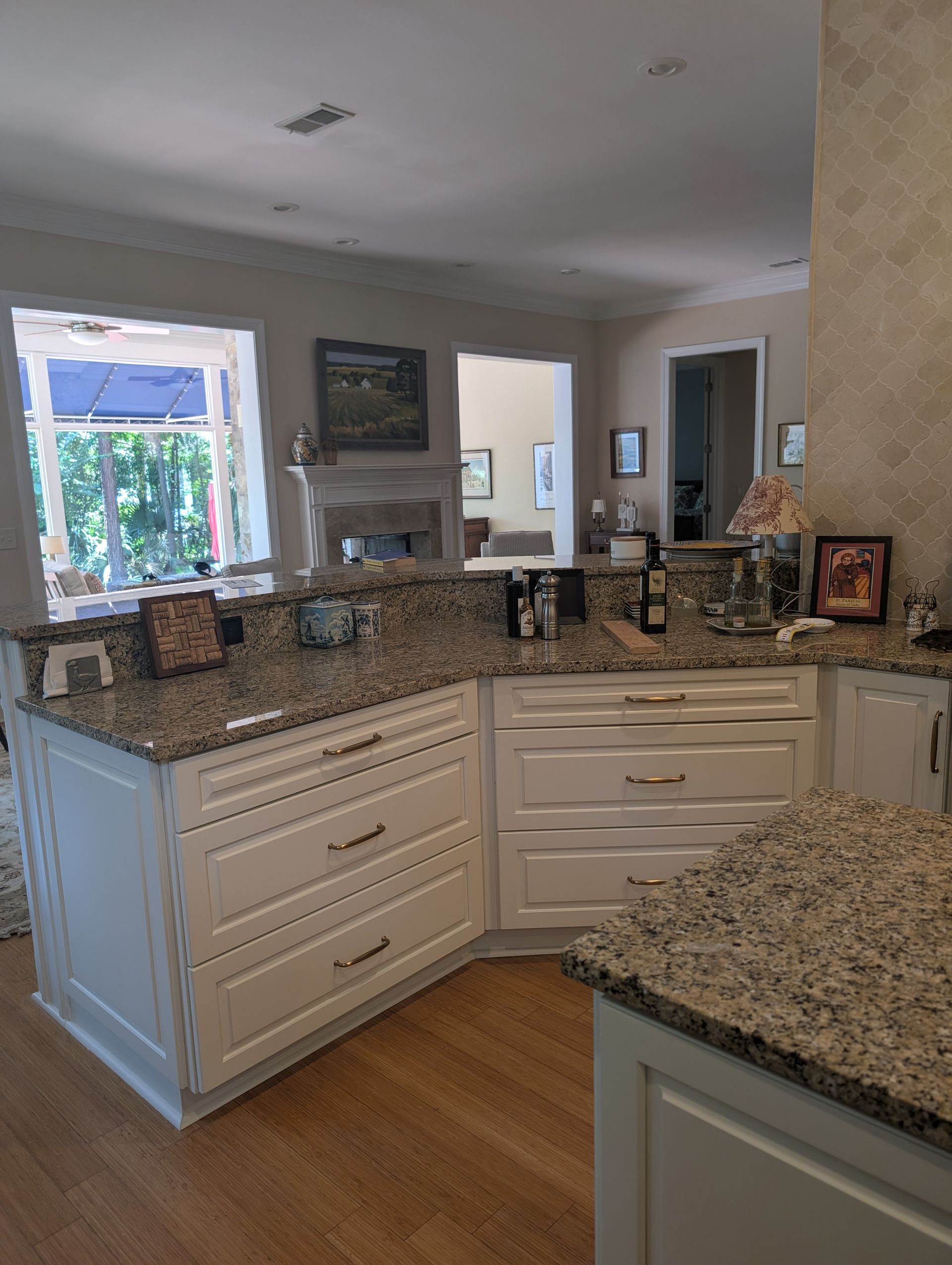 White kitchen cabinets with granite countertops. Sunlight streams through a window.