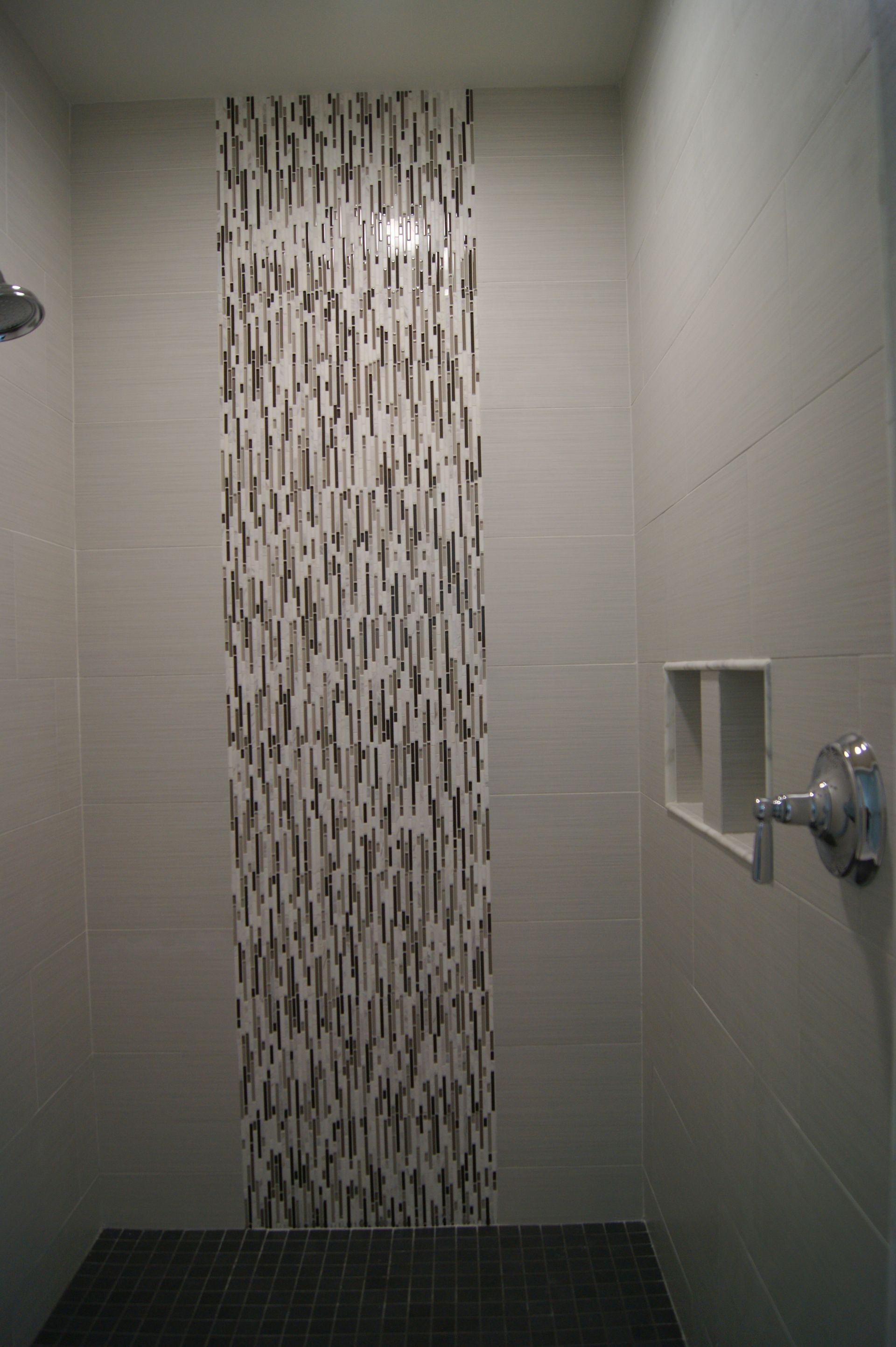 Shower with gray and patterned tile accent. Includes a niche and showerhead.