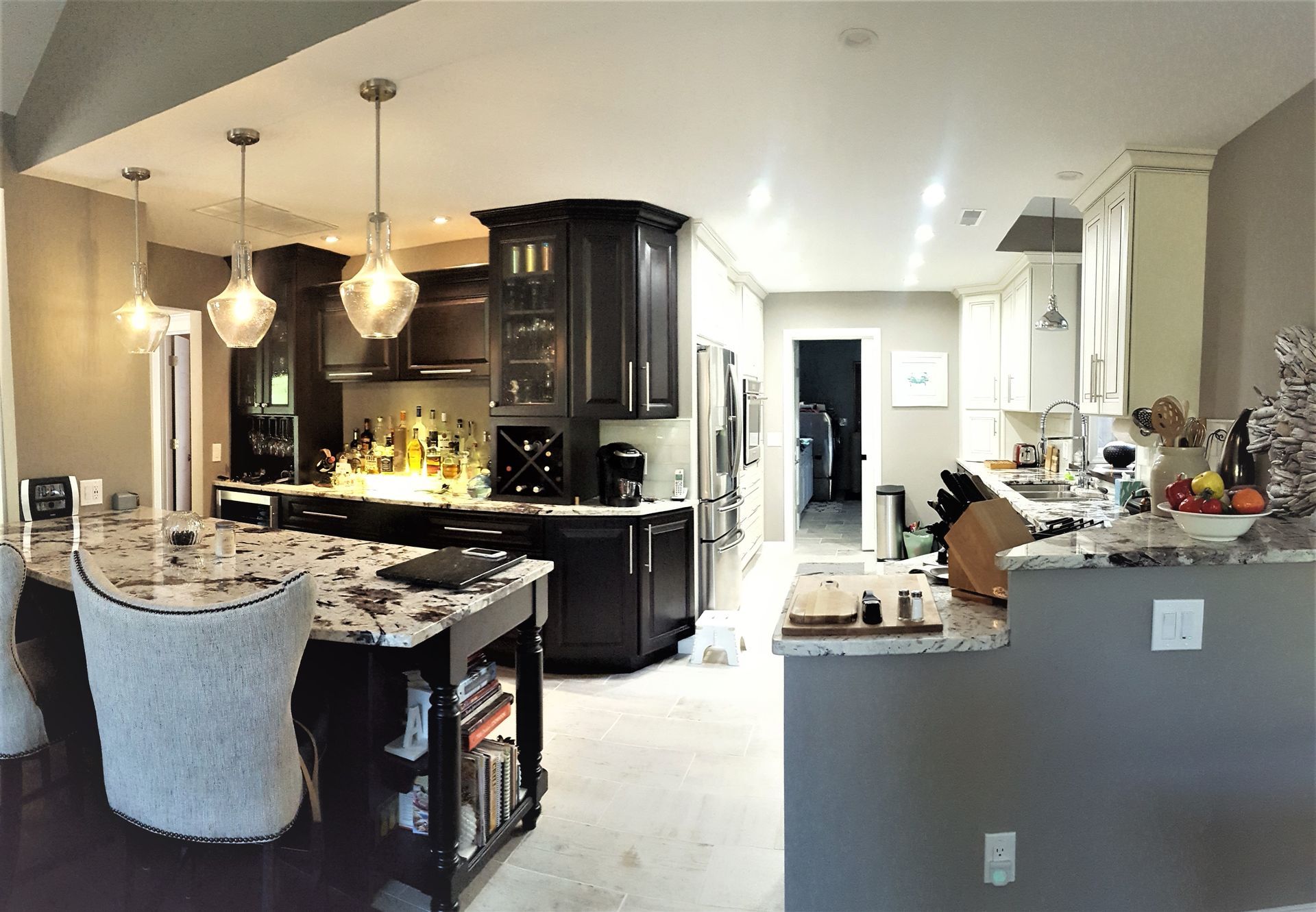 Spacious kitchen with dark cabinets, granite countertops, an island with seating, and pendant lights.