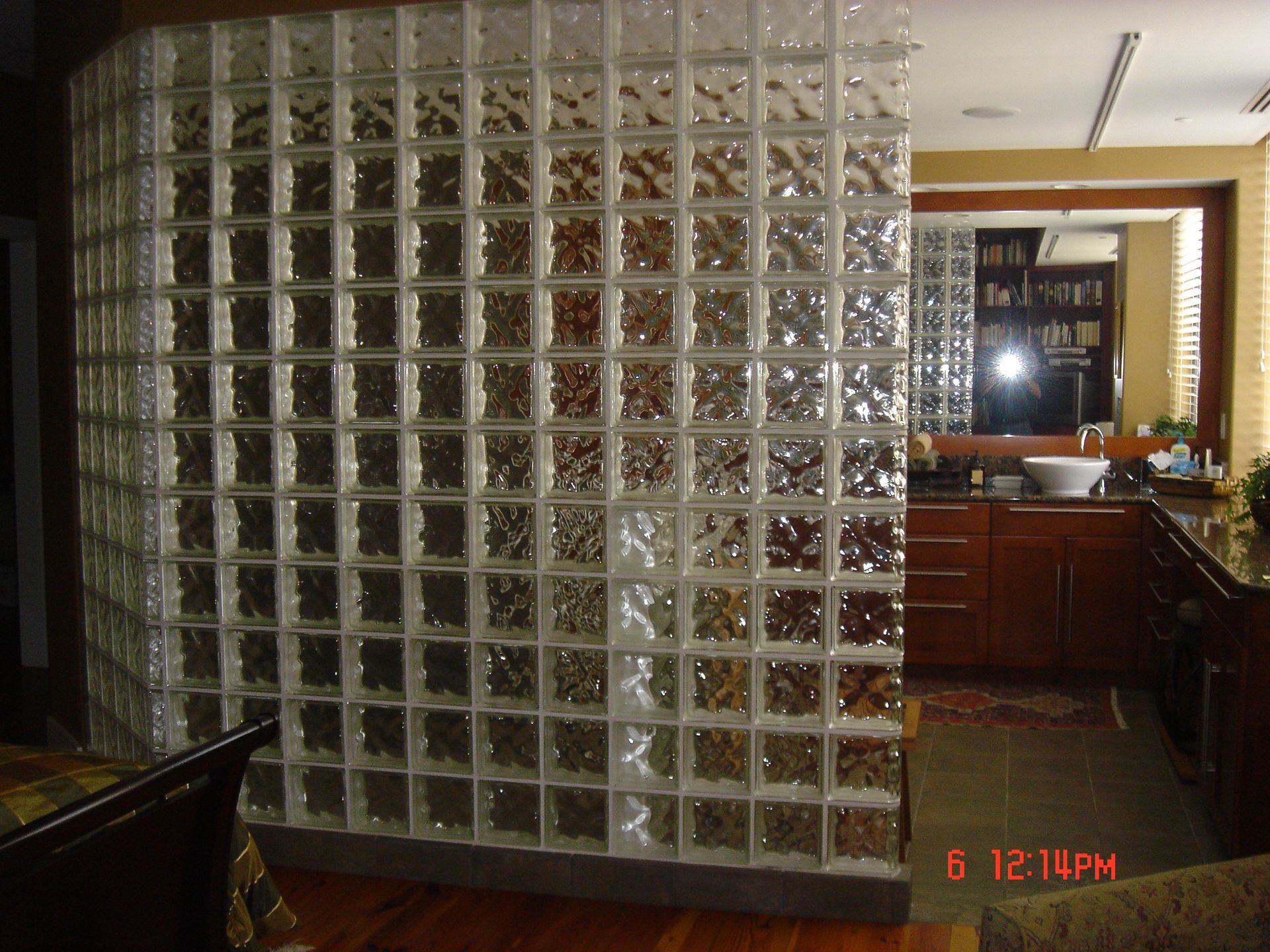 Glass block wall separating a bathroom from a room; wood cabinets and countertop visible.