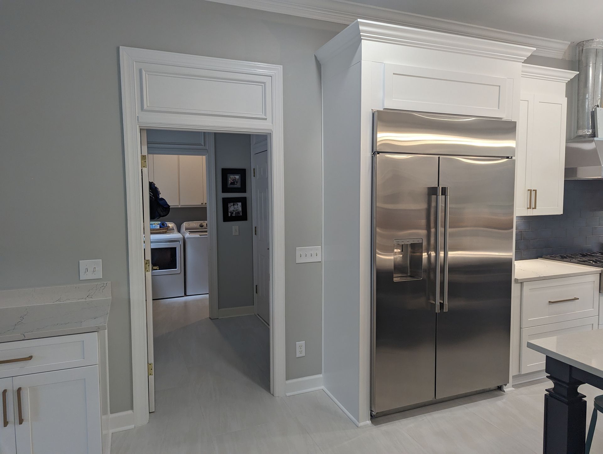Kitchen with white cabinets, stainless steel refrigerator, and a doorway to a laundry room.