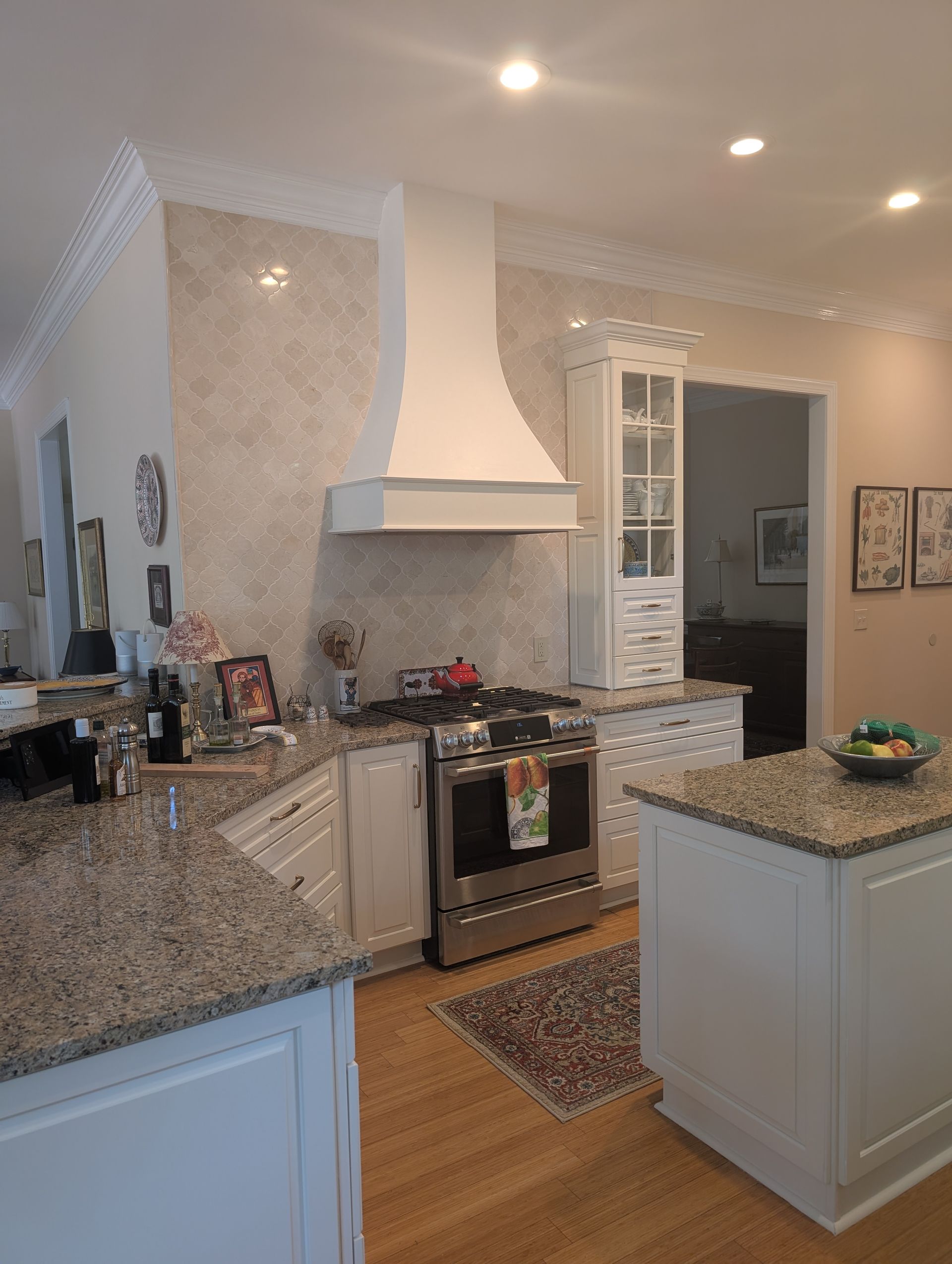 Kitchen with white cabinets, granite countertops, stainless steel stove, and white range hood.