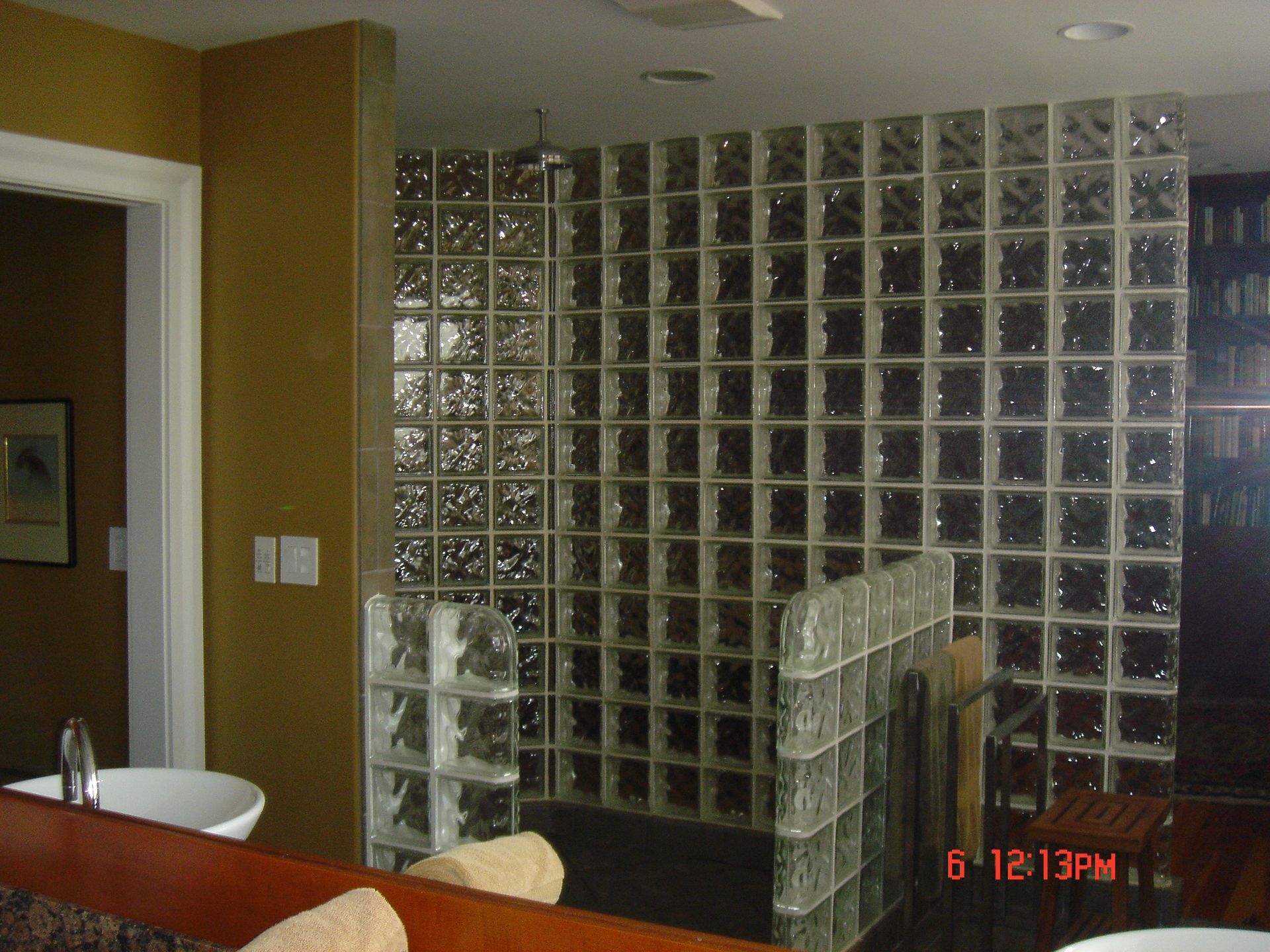 Glass block wall in a room, with a sink and doorway visible.