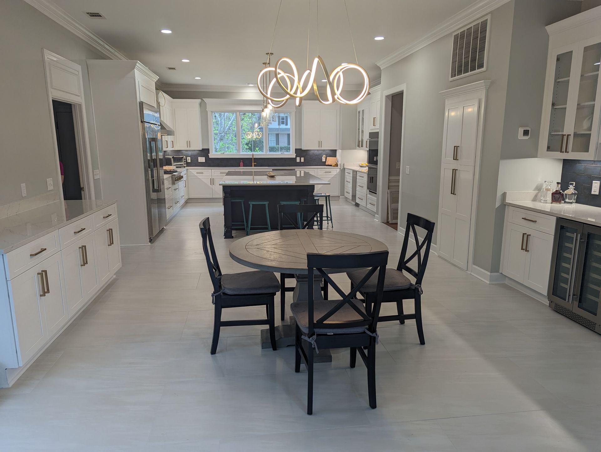 Open-concept kitchen with white cabinets, island, and circular dining table with black chairs.
