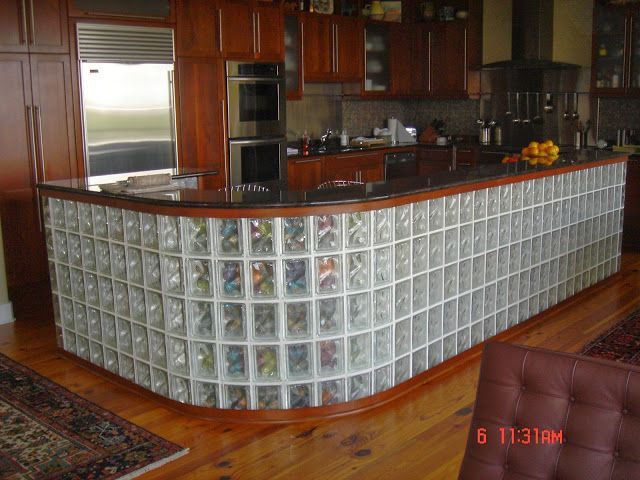 Kitchen island with glass block base, dark wood trim, granite countertop, and matching cabinetry.