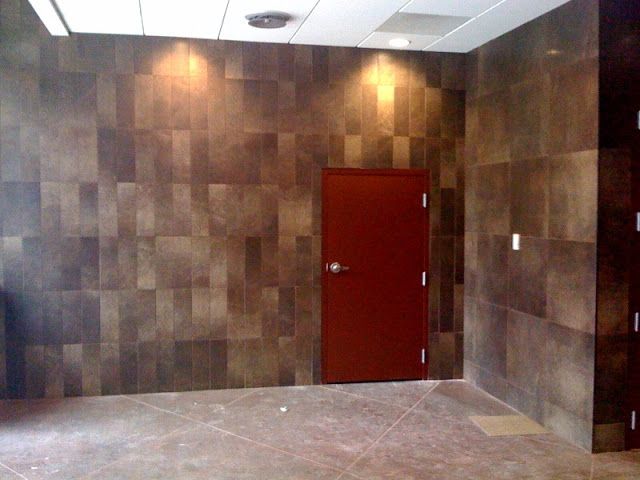 Brown tiled walls, red door, and recessed lighting in a commercial space.