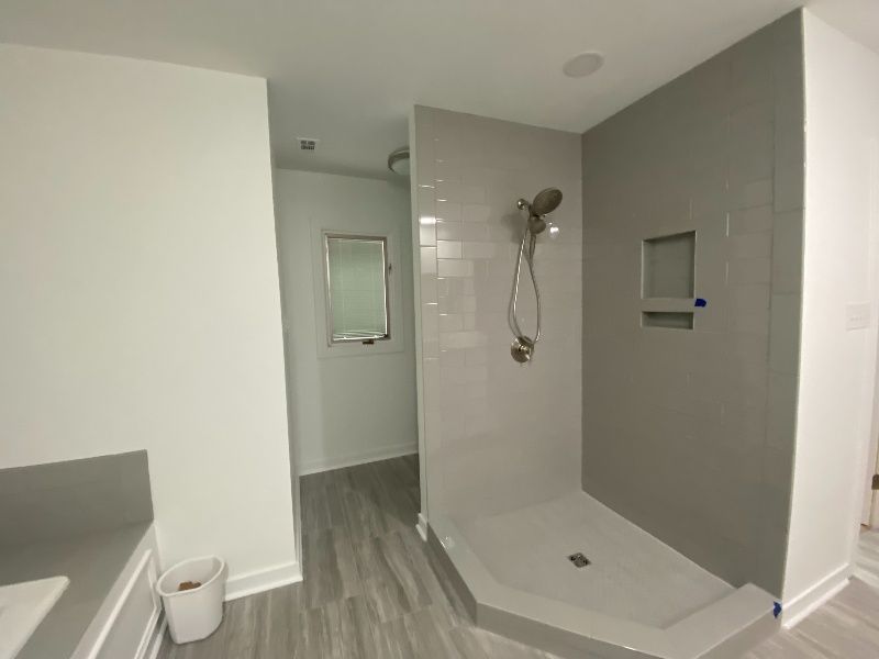 Bathroom with gray tiled shower, walk-in design. Gray walls, white trim and sink.
