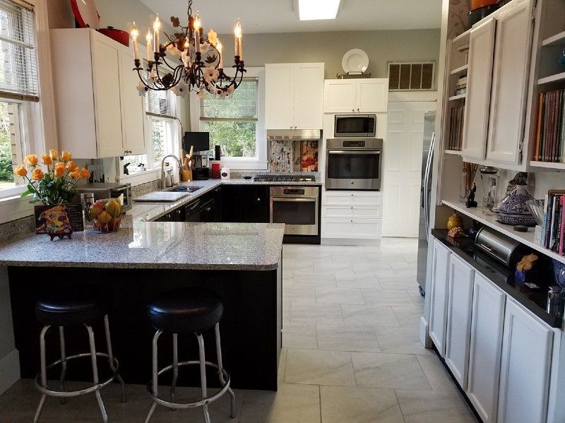 Kitchen with white cabinets, dark island, stainless appliances, and a chandelier.