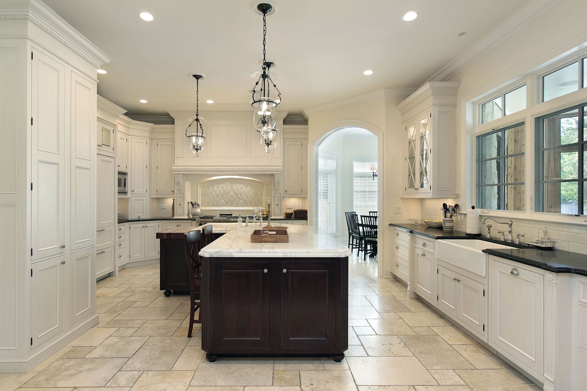 Elegant white kitchen with dark wood island and pendant lights.