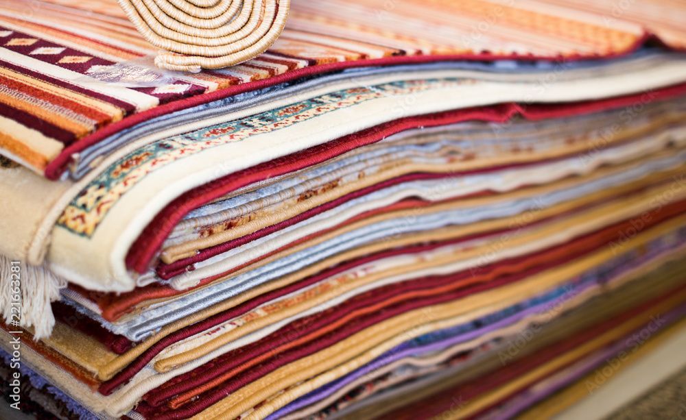 A stack of colorful rugs sitting on top of each other on a table.