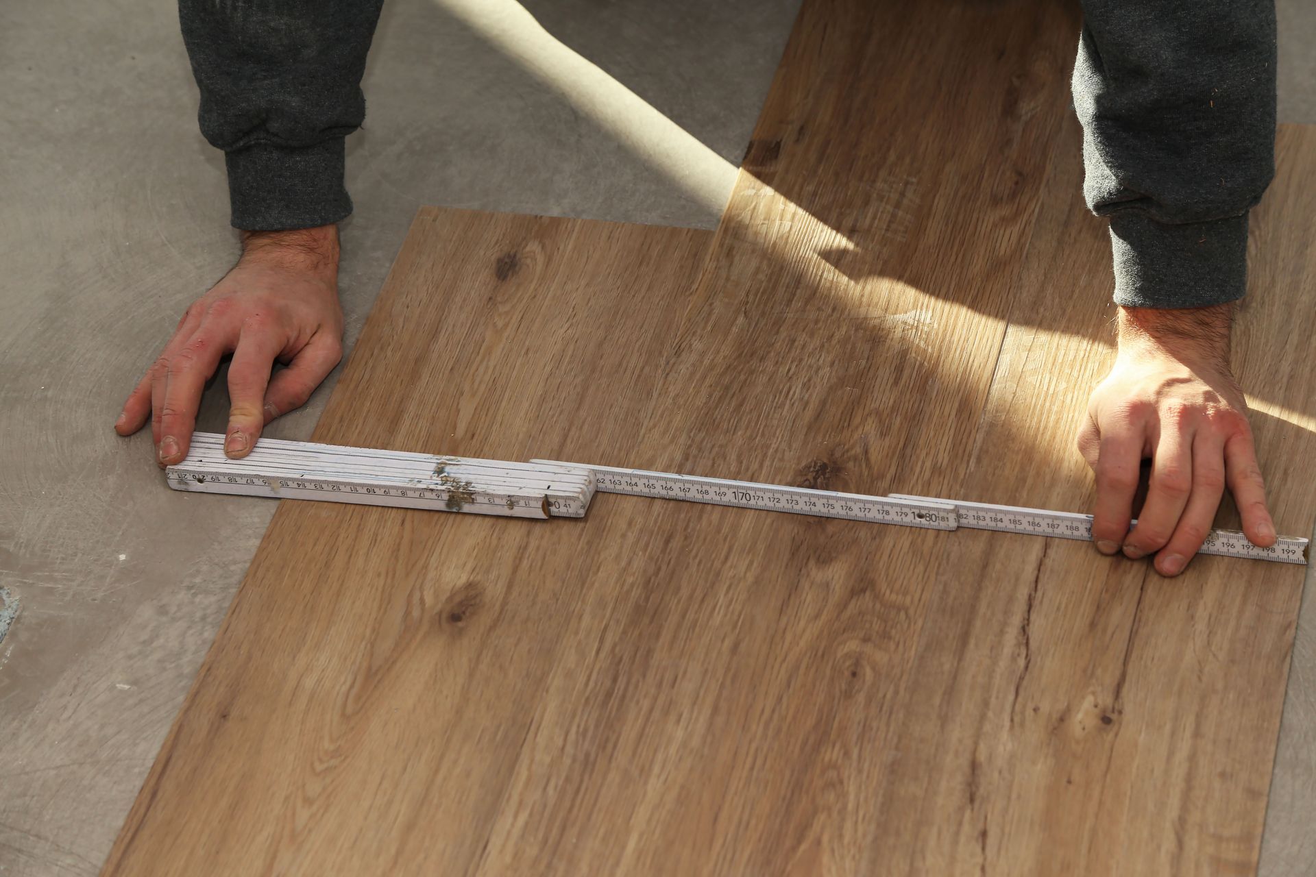 A person is measuring a piece of wood with a ruler.