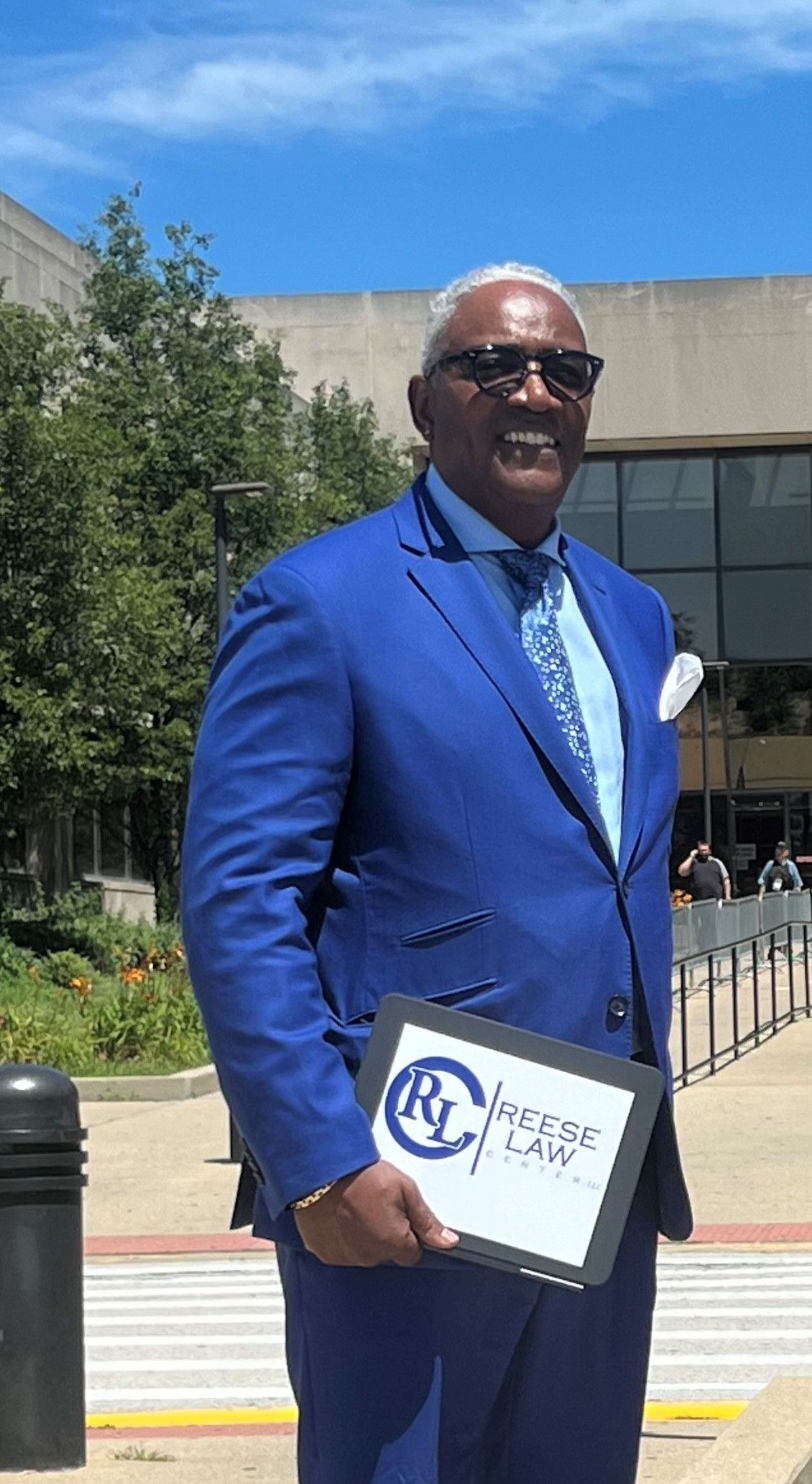 A man in a blue suit and tie is holding a sign in front of a building.