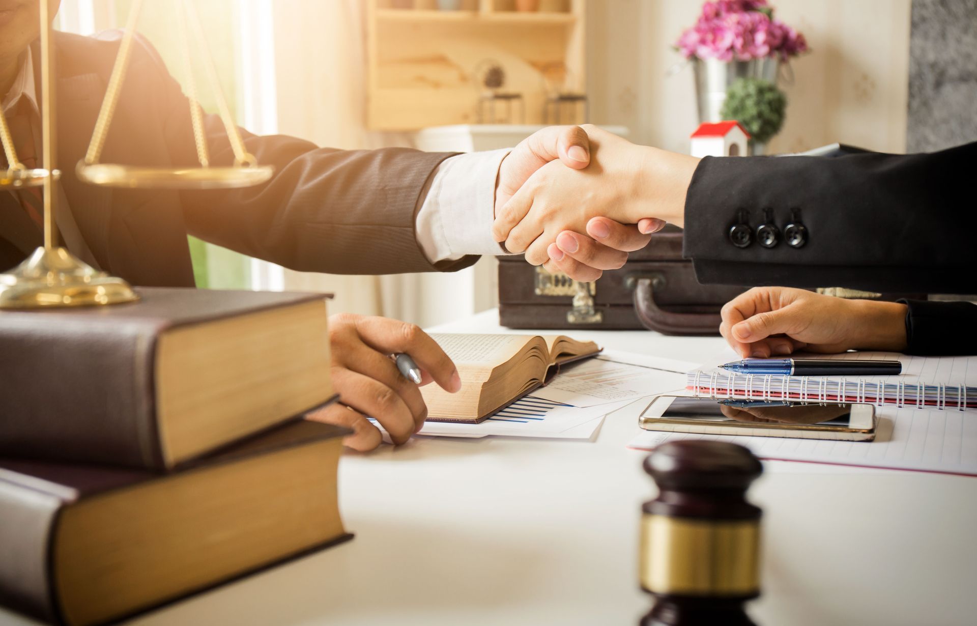 A lawyer is shaking hands with a client while sitting at a table.