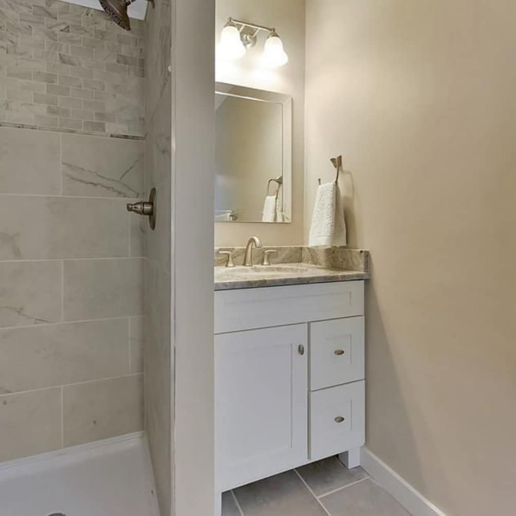 A bathroom with a sink, mirror and shower.