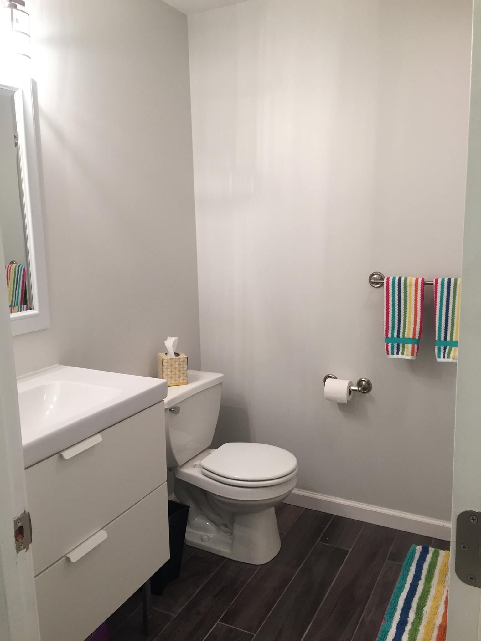 A bathroom with a toilet, sink and mirror.