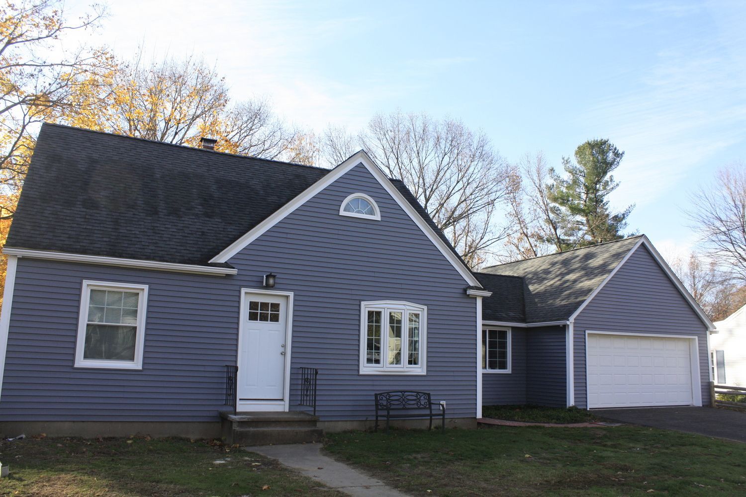 A gray house with a black roof and a white garage door.