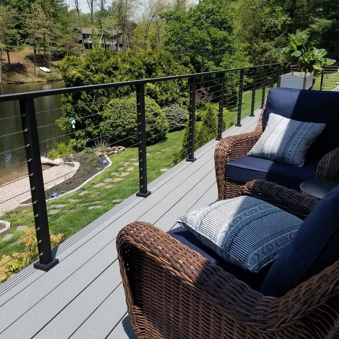 Two wicker chairs on a deck overlooking a lake