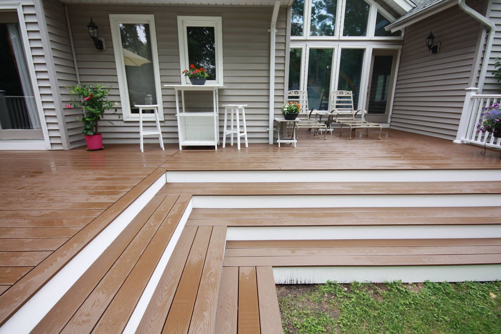 A wooden deck with stairs leading up to it in front of a house.