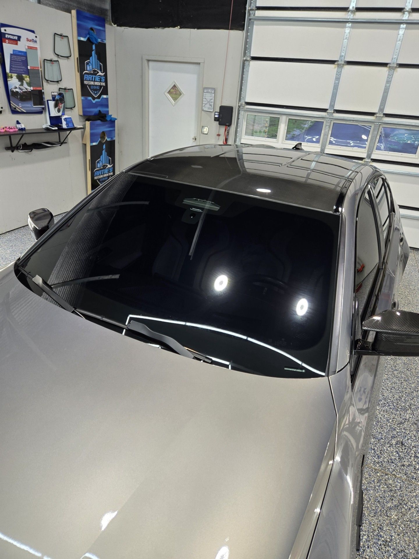A gray car with tinted windows inside a garage.