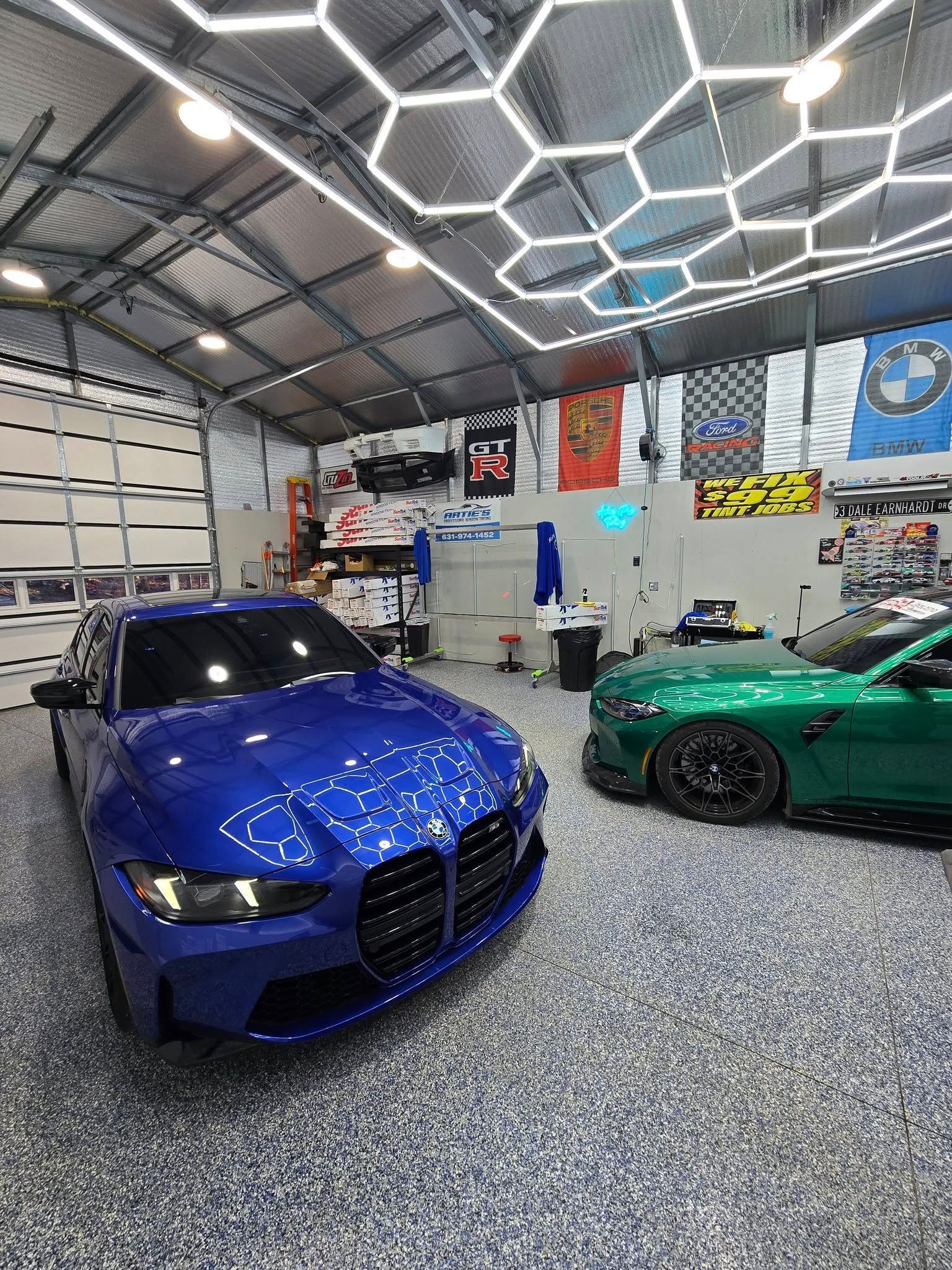 A blue car and a green car are parked in a garage.