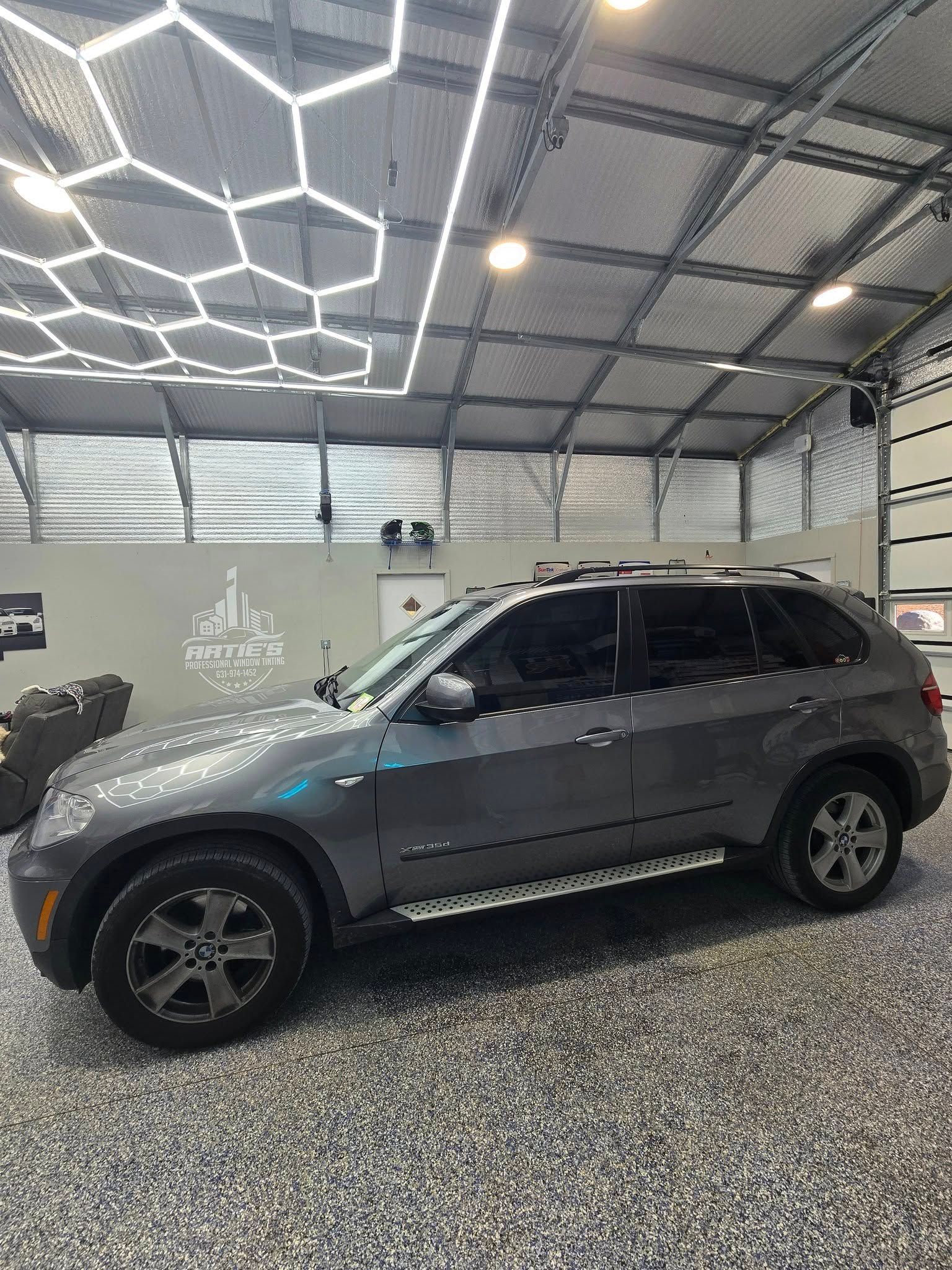 A gray bmw x5 is parked in a garage.