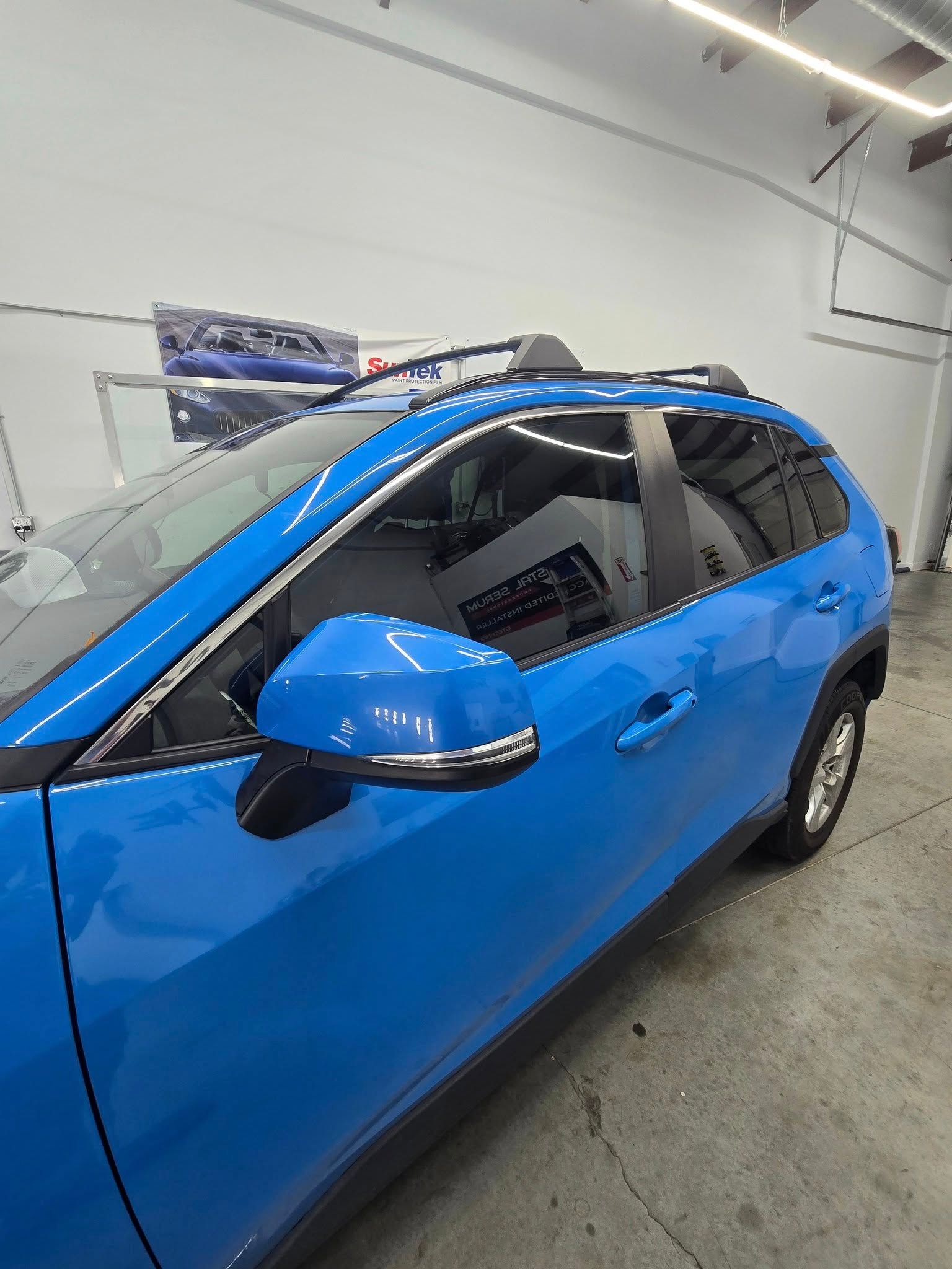 A blue car is parked in a garage with a roof rack.