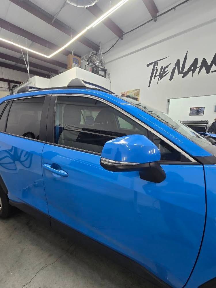 A blue car is parked in a garage next to a sign that says the nans.