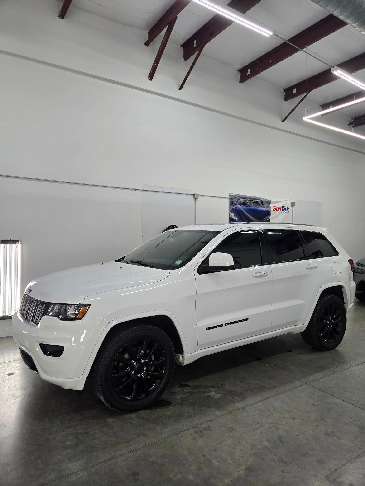 A white jeep grand cherokee is parked in a garage.