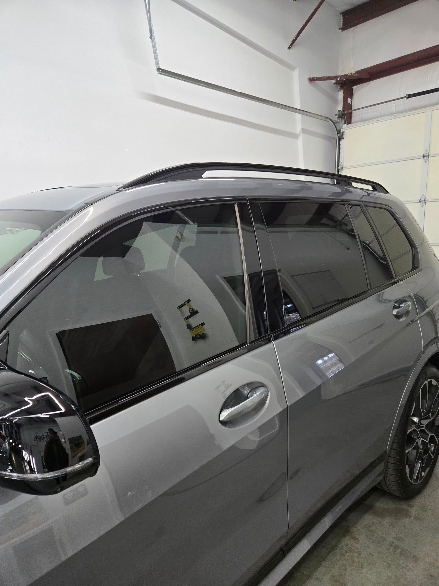 A gray car is parked in a garage next to a garage door.