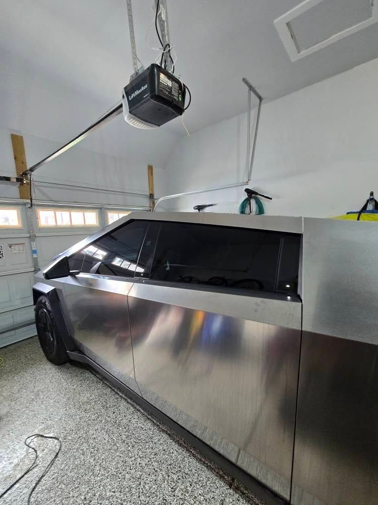 A silver car is parked in a garage under a garage door opener.