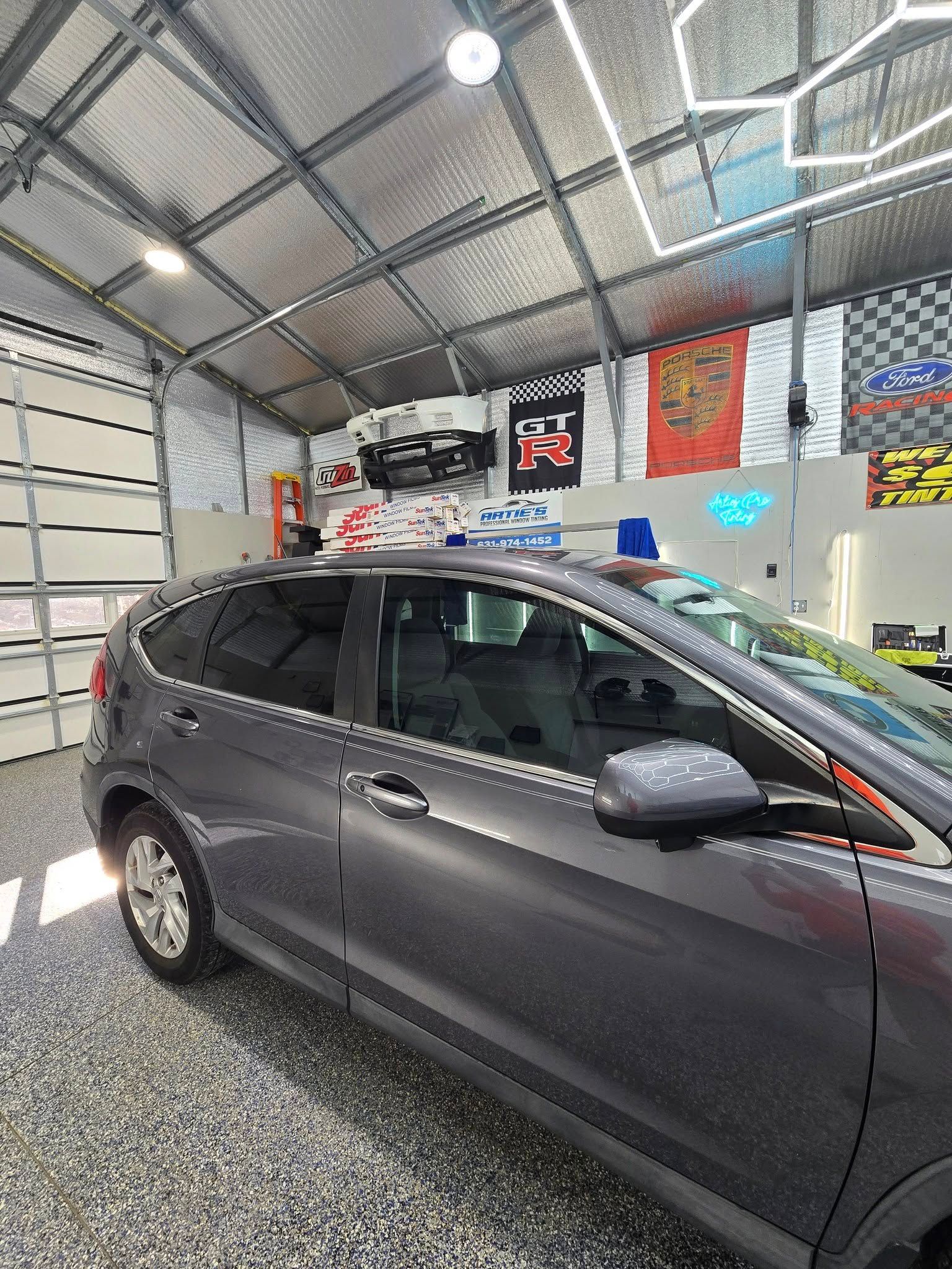 A gray car is parked in a garage next to a garage door.