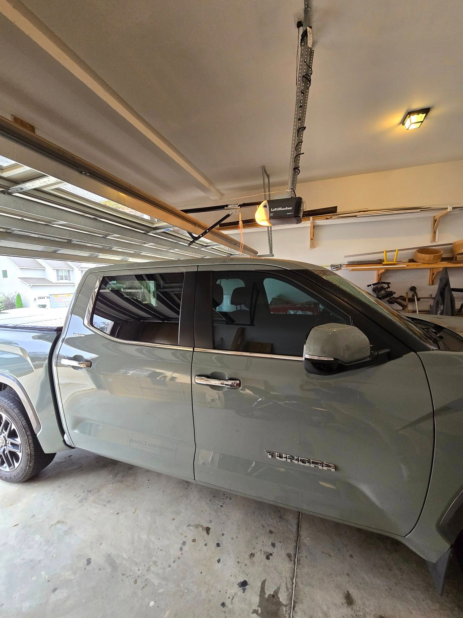 A truck is parked in a garage with a garage door open.