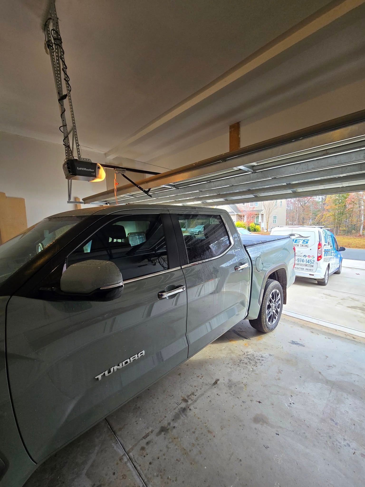 A truck is parked in a garage with a garage door open.