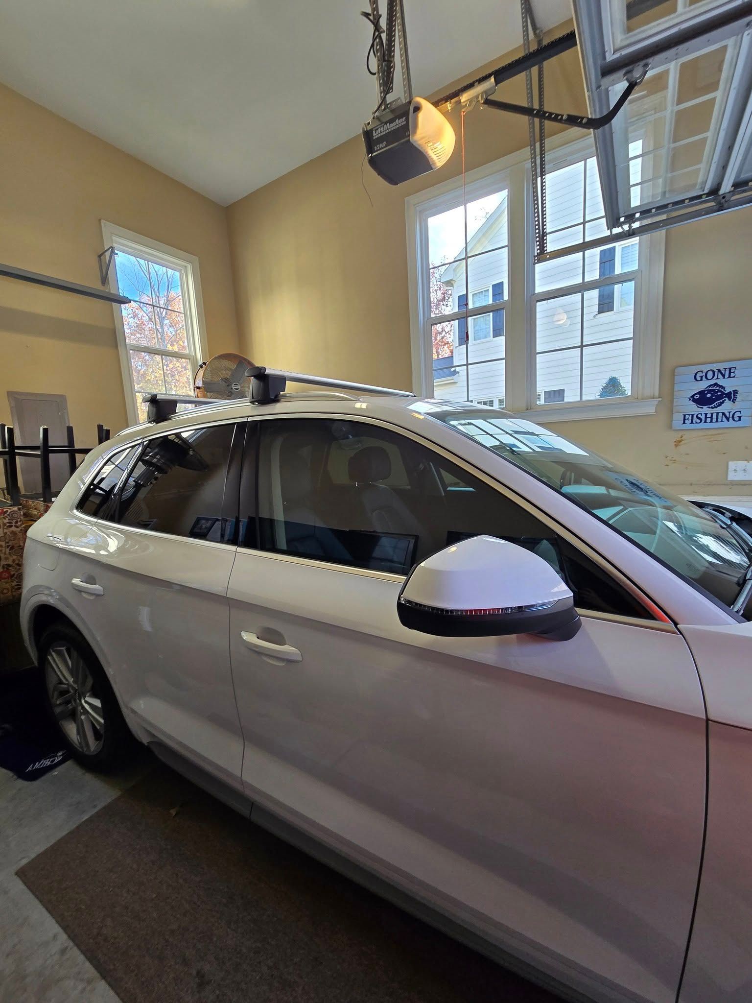 A white car is parked in a garage with a roof rack.