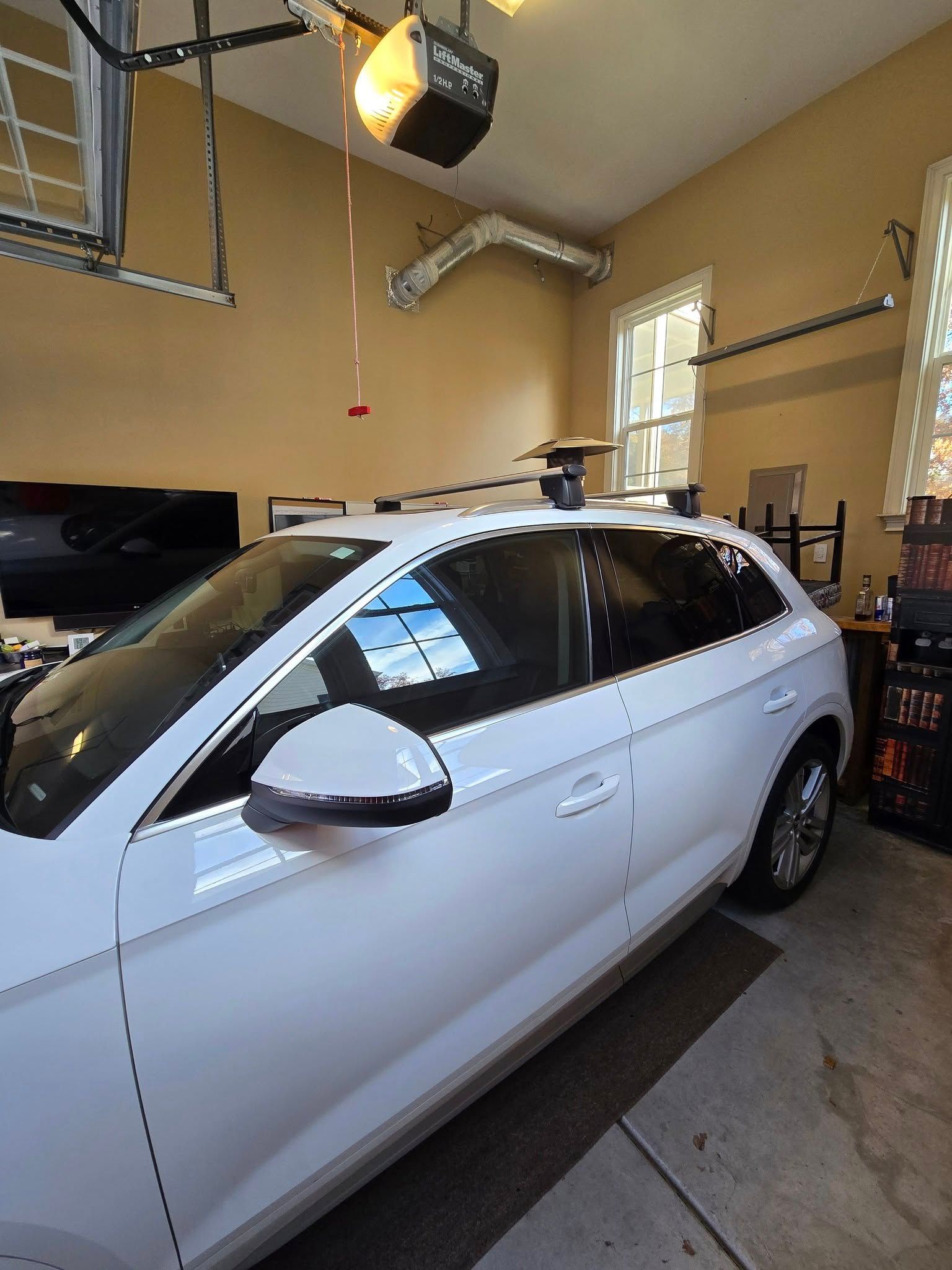 A white car is parked in a garage under a garage door opener.