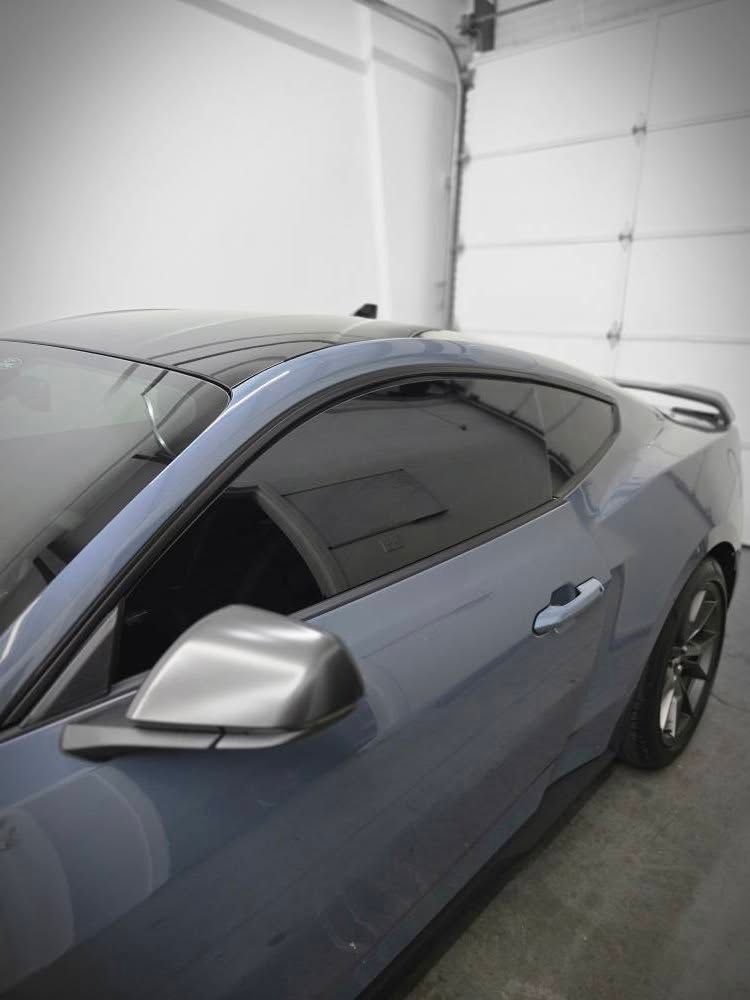 A blue mustang is parked in a garage next to a garage door.