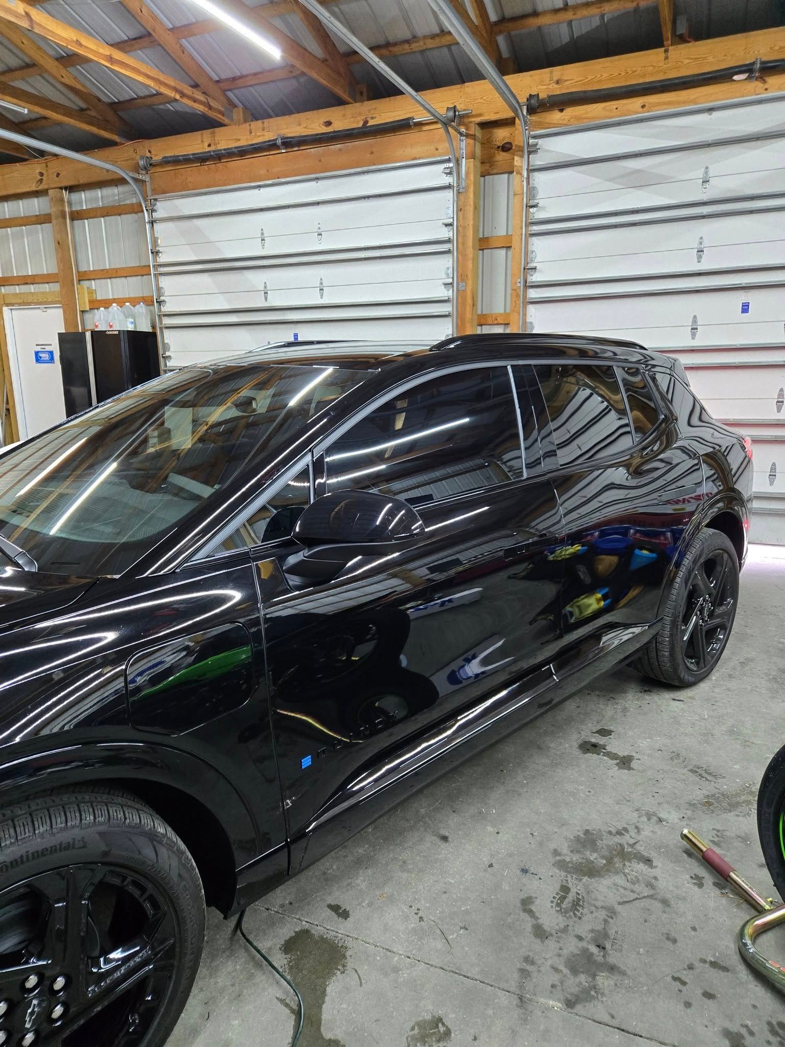 A black car is parked in a garage next to a motorcycle.