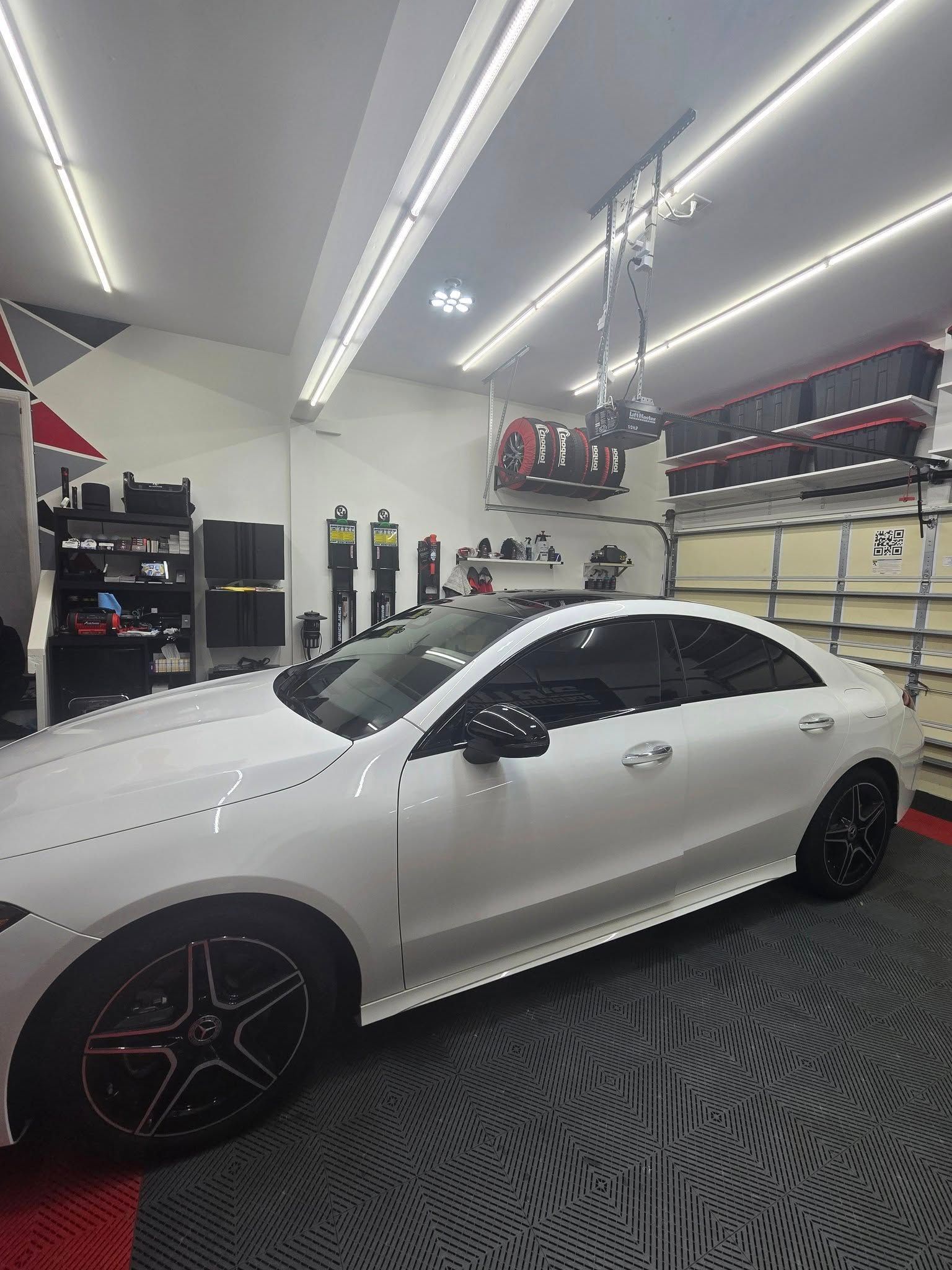 A white car is parked in a garage with a garage door opener.