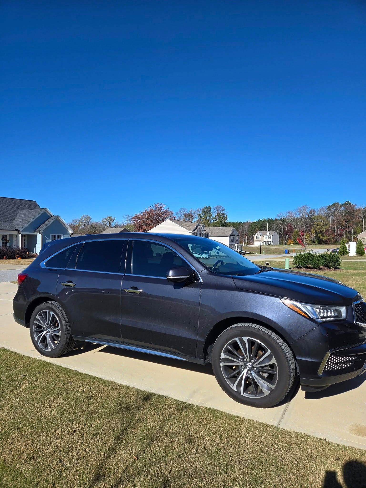 A black suv is parked on the side of the road in front of a house.