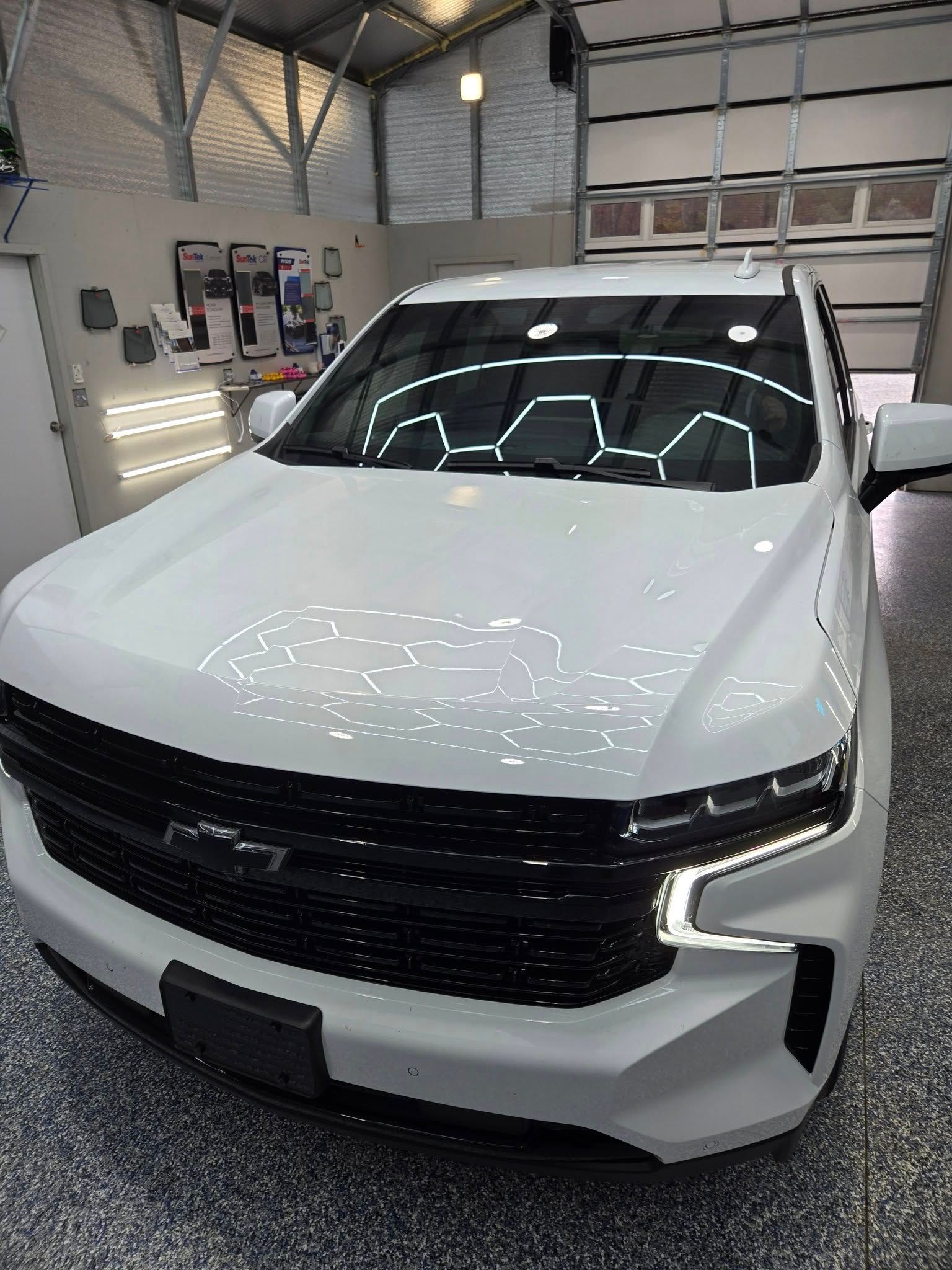 A white truck is parked in a garage next to a garage door.
