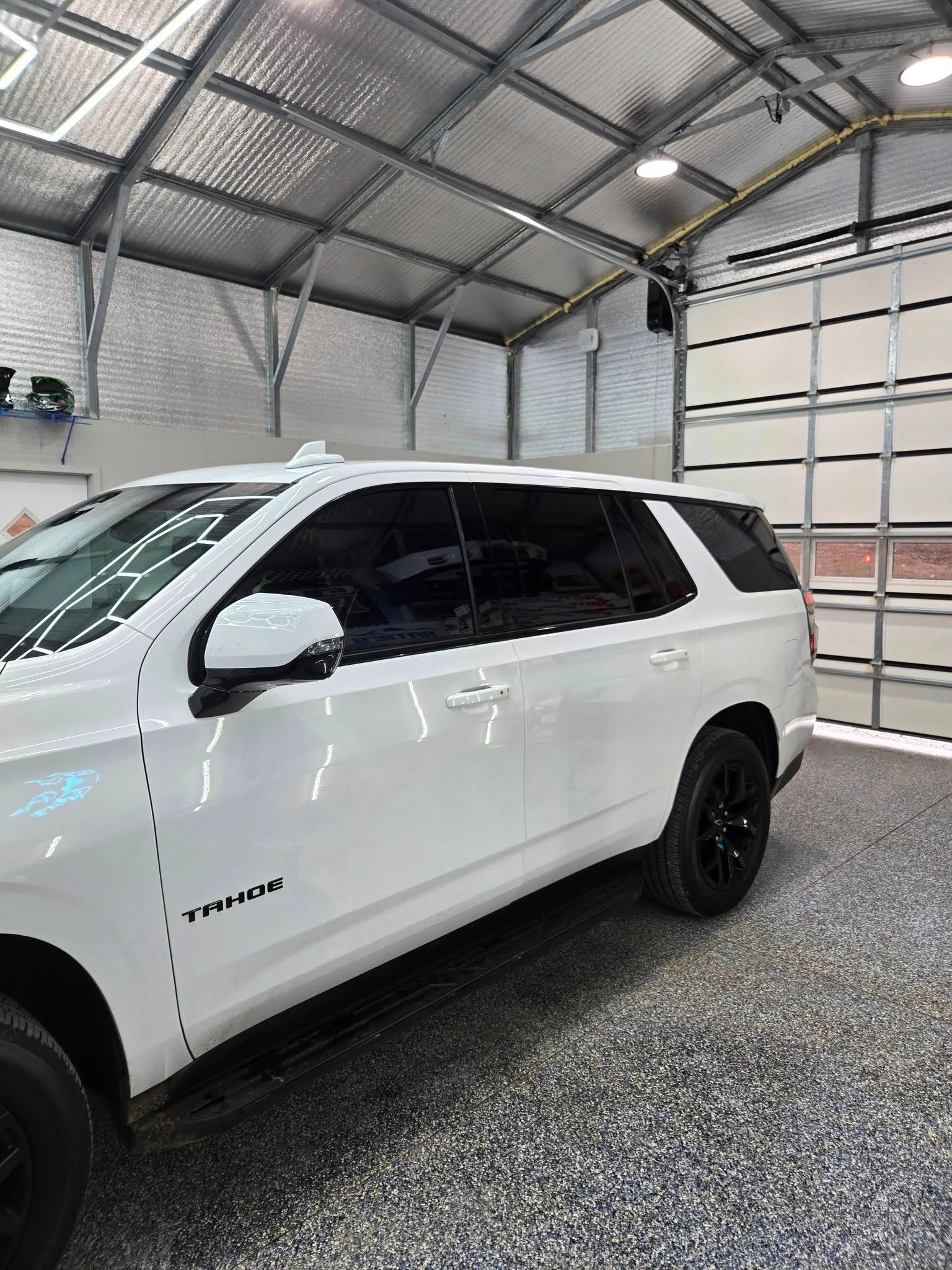 A white suv is parked in a garage next to a garage door.