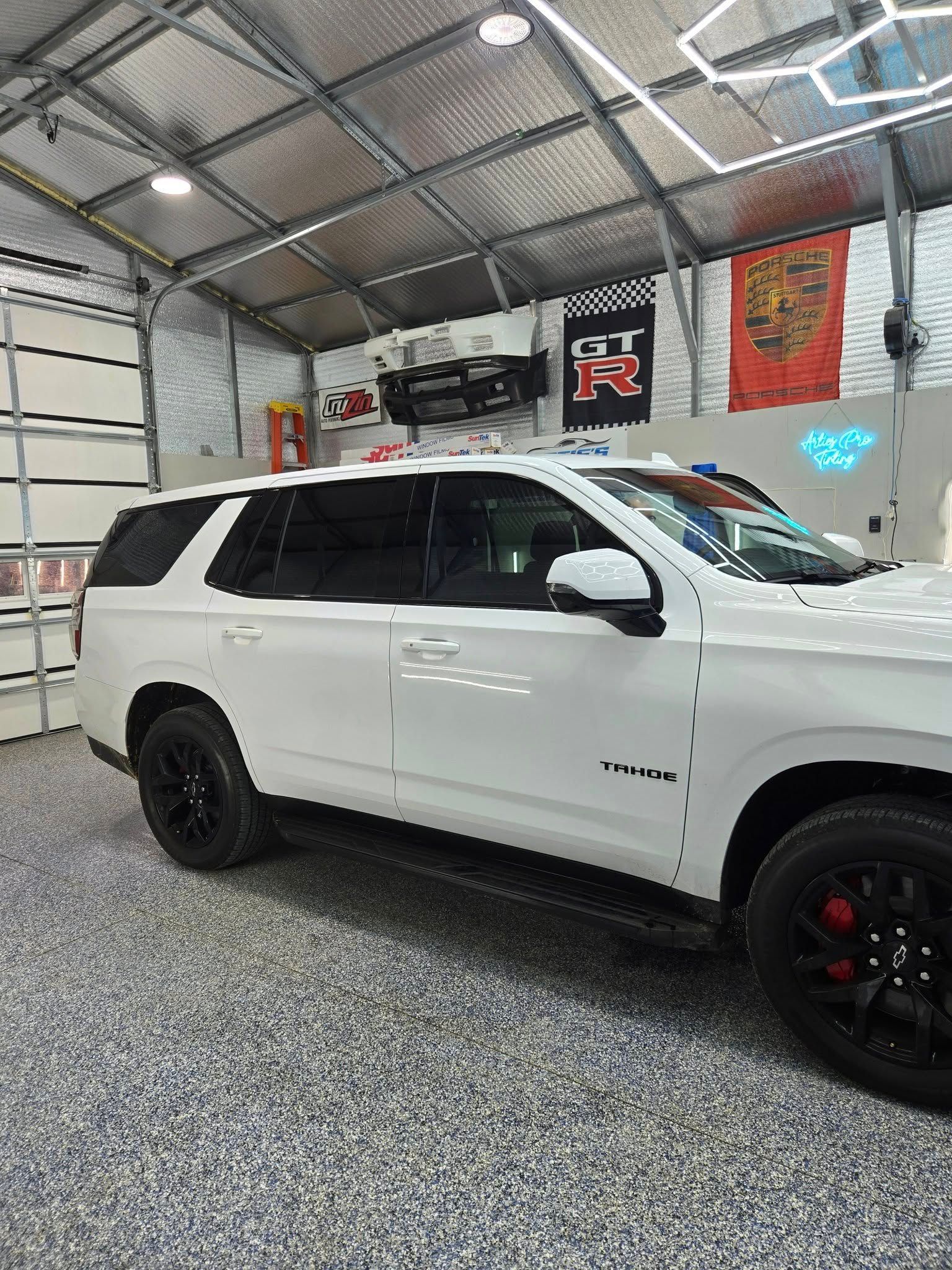 A white suv is parked in a garage next to a garage door.