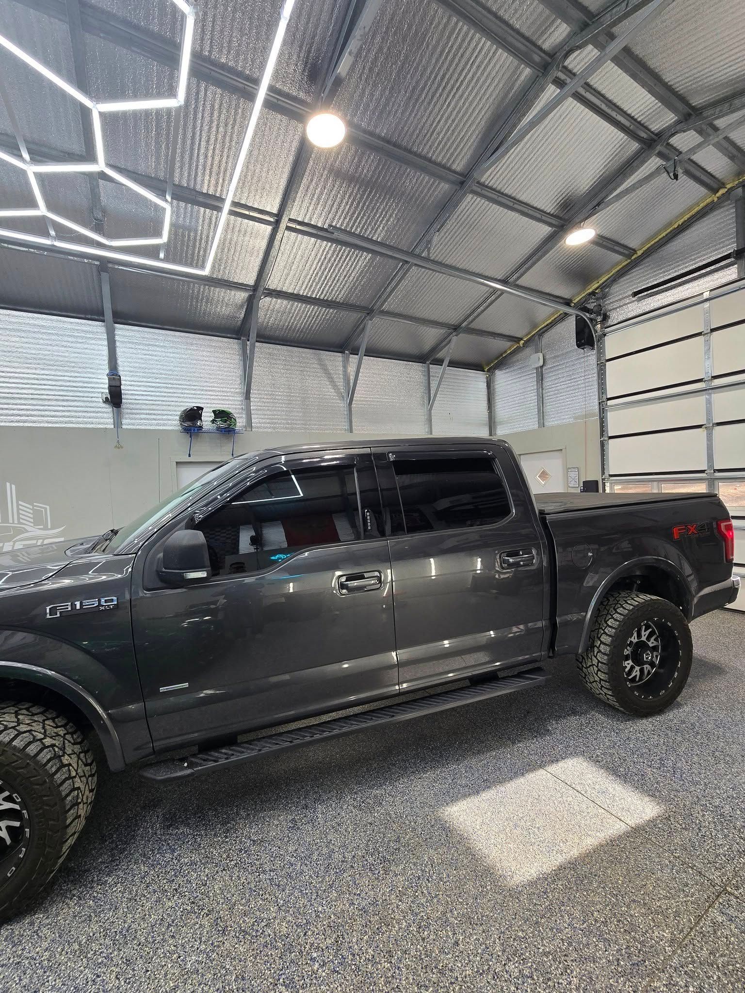 A gray pickup truck is parked in a garage.