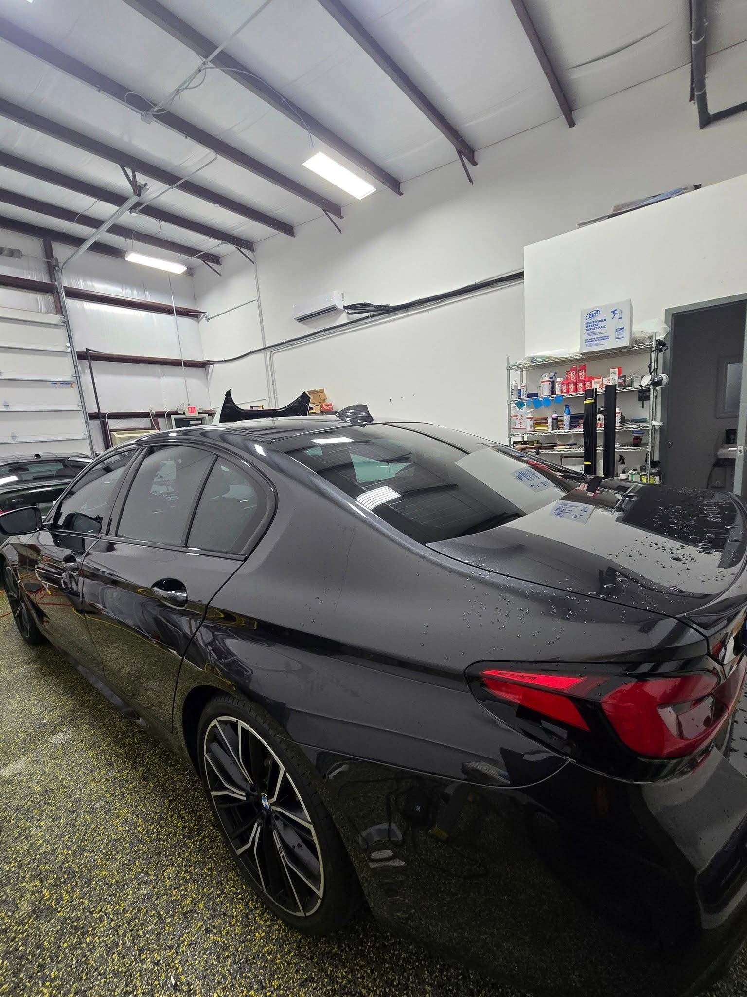 A black car is parked in a garage next to a garage door.