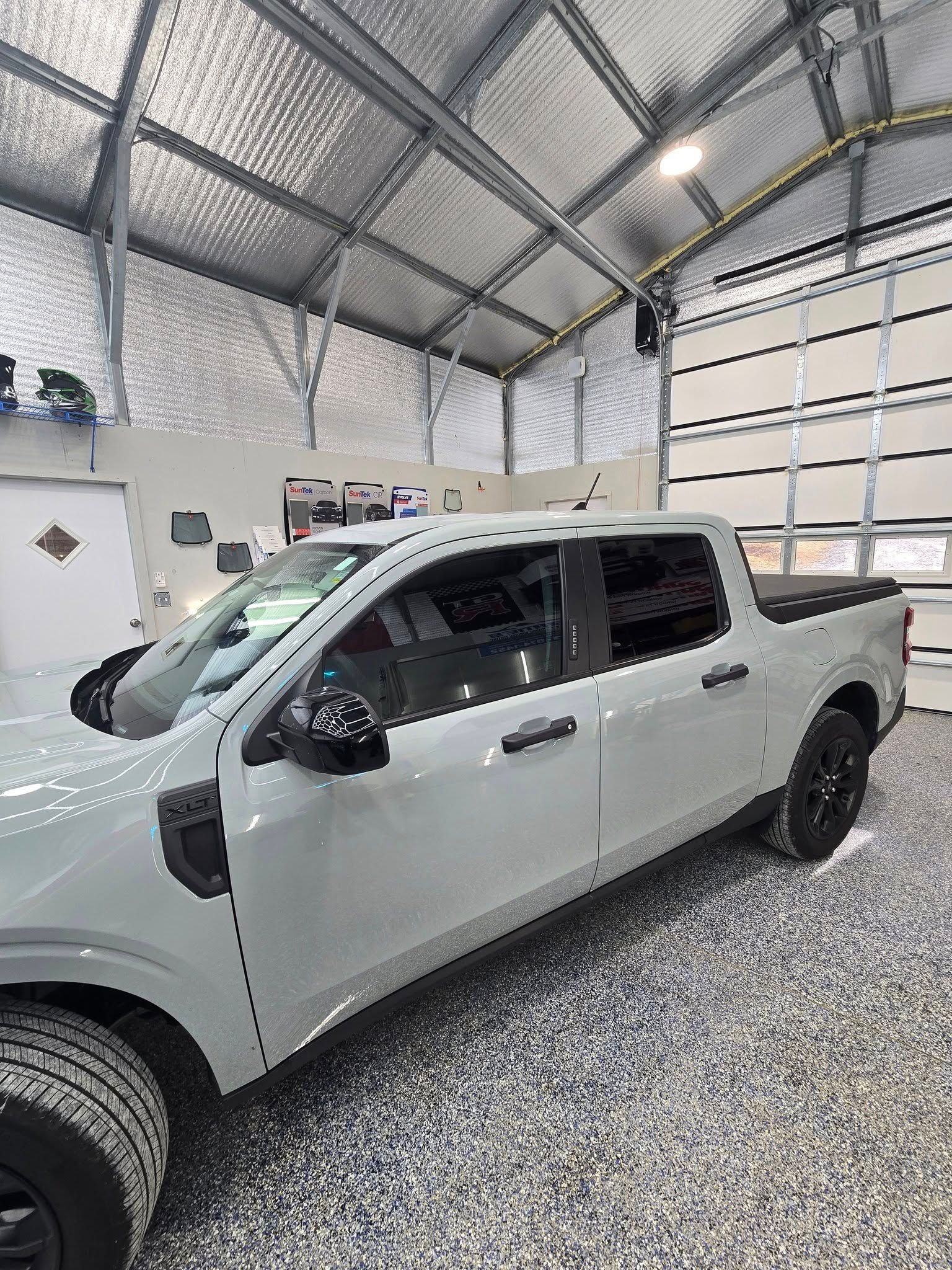 A white truck is parked in a garage next to a garage door.