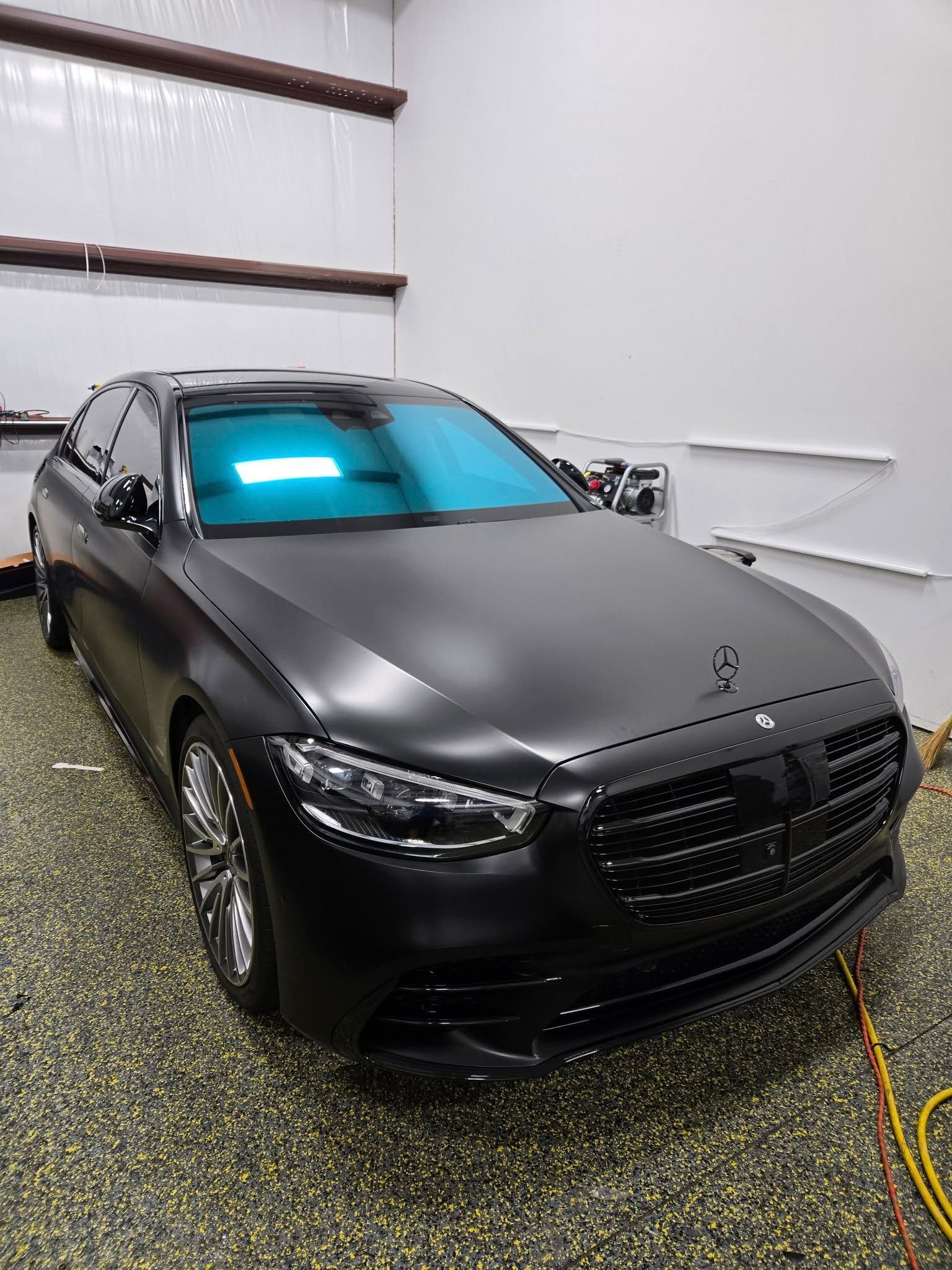 A black mercedes benz s class is parked in a garage.