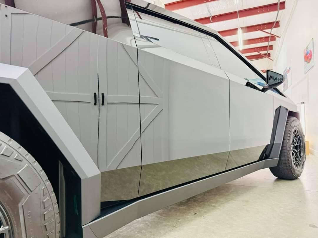 A silver car with a large tire is parked in a garage.