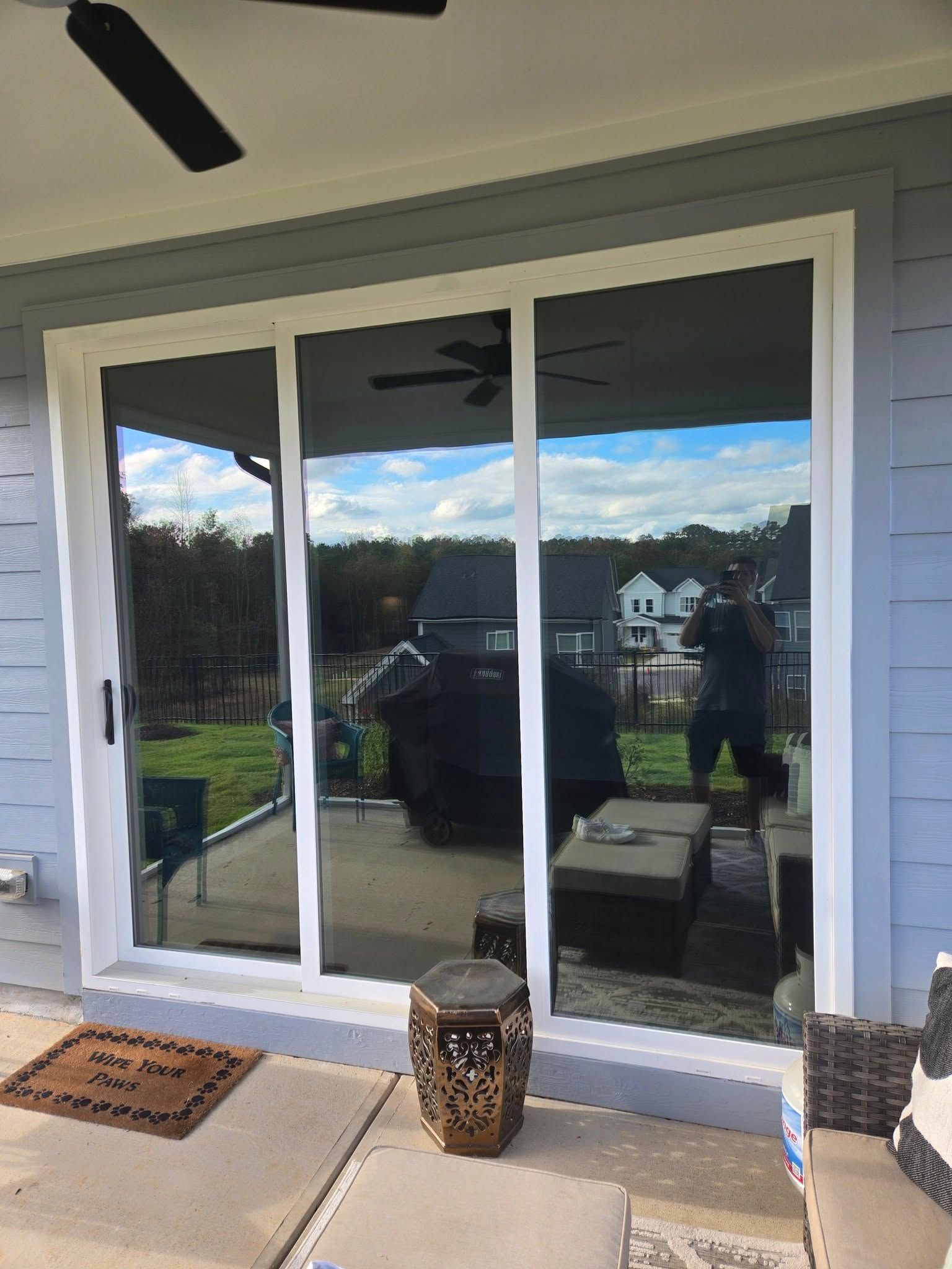 A sliding glass door is open to a patio with a ceiling fan.