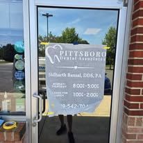 A person is standing in front of a dental office door with a sign on it.