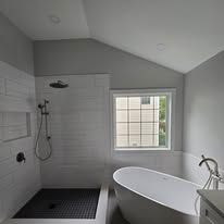 A bathroom with a tub , shower , and window.